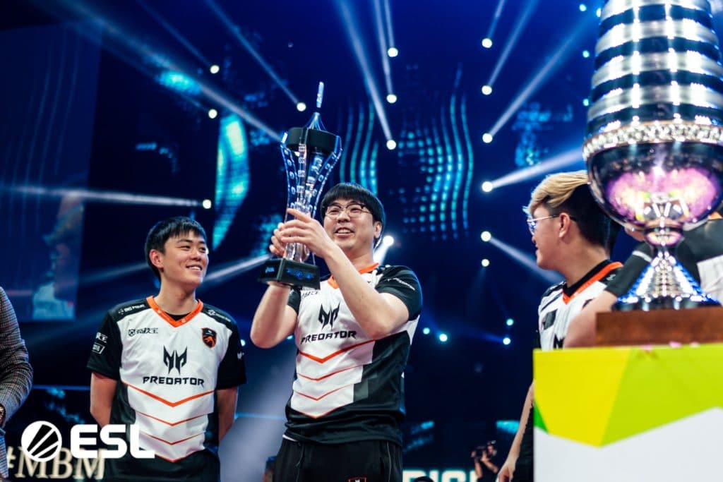 Players from TNC.Predator hold aloft the ESL One Trophy on the stage at Hamburg