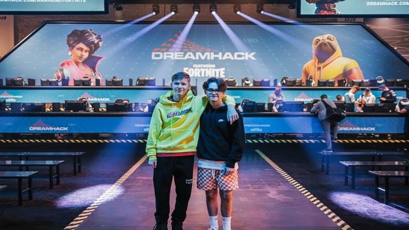 MrSavage and Rehx stand with arms over each others shoulders in front of the DreamHack Anaheim stage