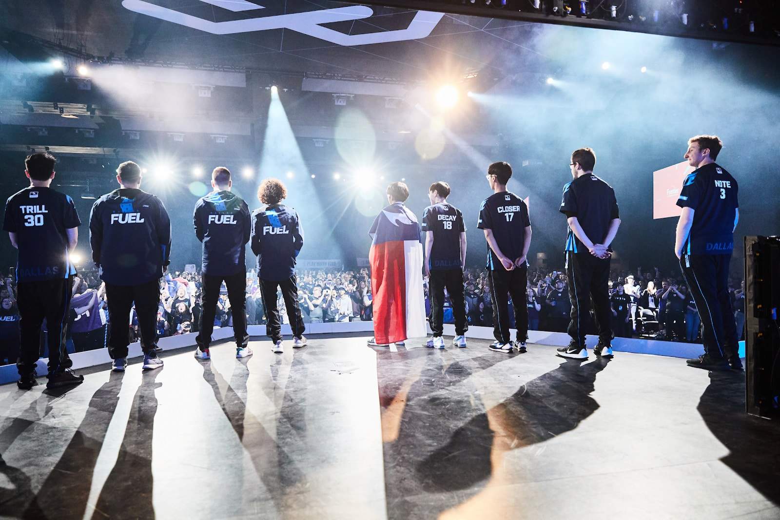 A shot from behind showing the Dallas Fuel on stage looking out at the crowd .