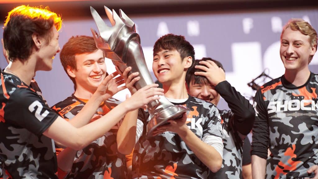 Architect holds up the OWL trophy on stage, surrounded by his fellow team mates
