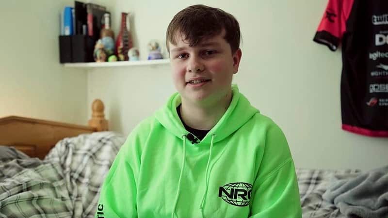 Pro Fortnite player Benjyfishy in a green hoodie sitting on his bed