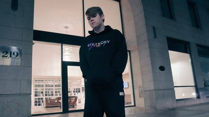 Pro Fortnite player Mongraal with his hands in his hoodie in front of a building