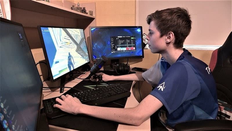 Pro Fortnite player Th0masHD in front of a three monitor computer setup