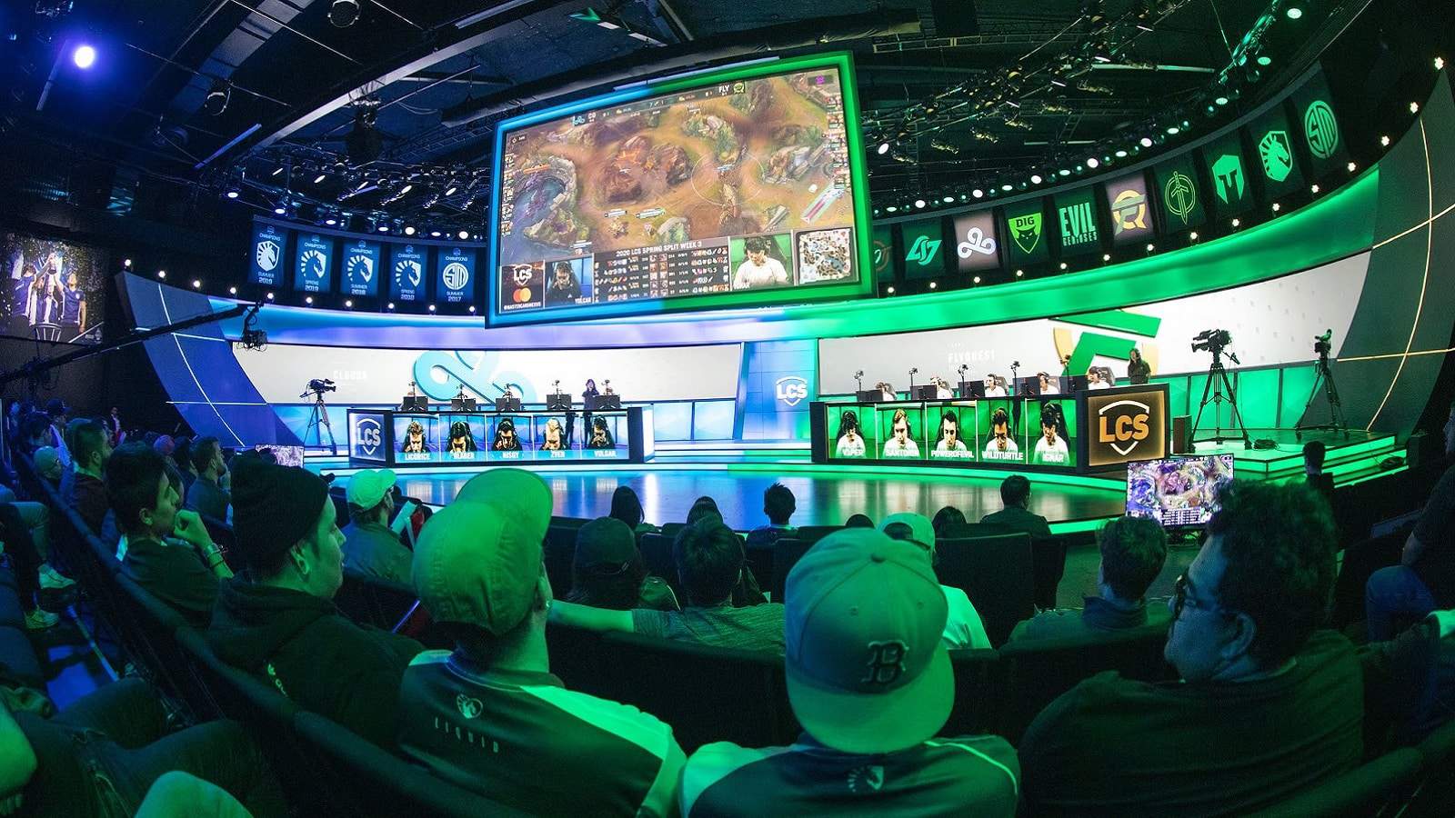 The LCS arena is packed with spectators and lit by blue and green lights as FlyQuest and Cloud9 face off