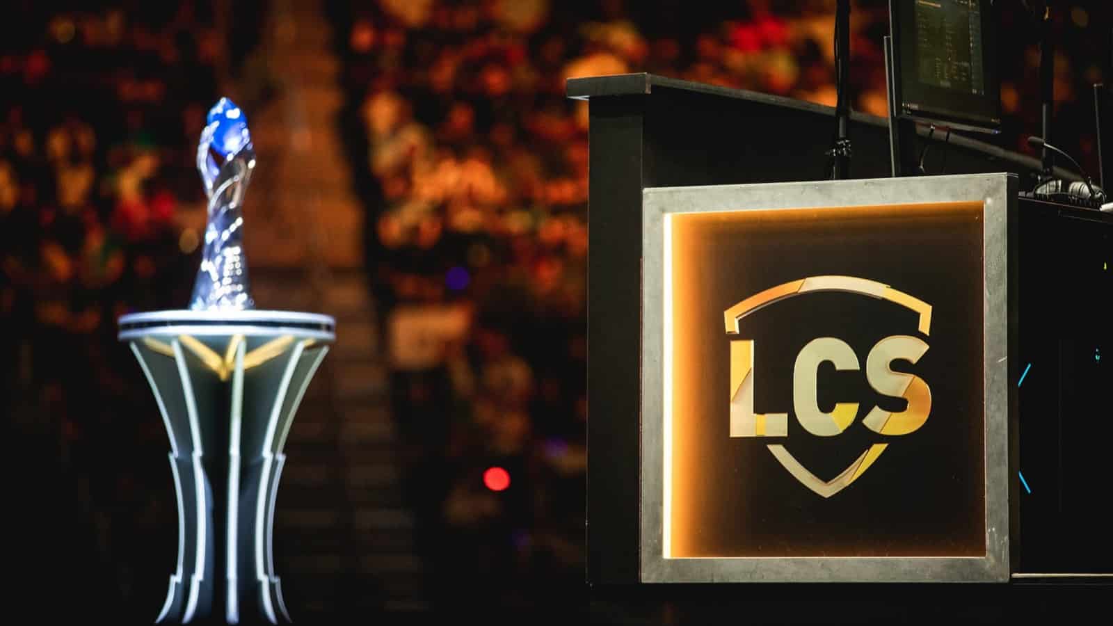 The LCS logo appears on a monitor near the LCS trophy with arena seating behind them