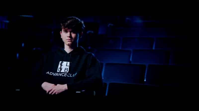 Pro Fortnite player Bugha sits in a theater chair in the dark with an AdvanceClub hoodie on