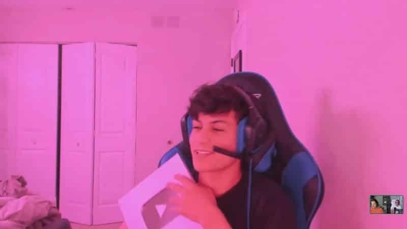 Pro Fortnite player Ronaldo holds a YouTube play button and smiles in his room