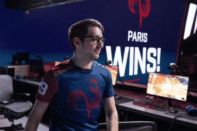 Paris Eternal Overwatch League player Terence "SoOn" Tarlier proudly walks on stage after a victory with a monitor in the background showing the Paris Eternal logo and the words "Paris Wins!"