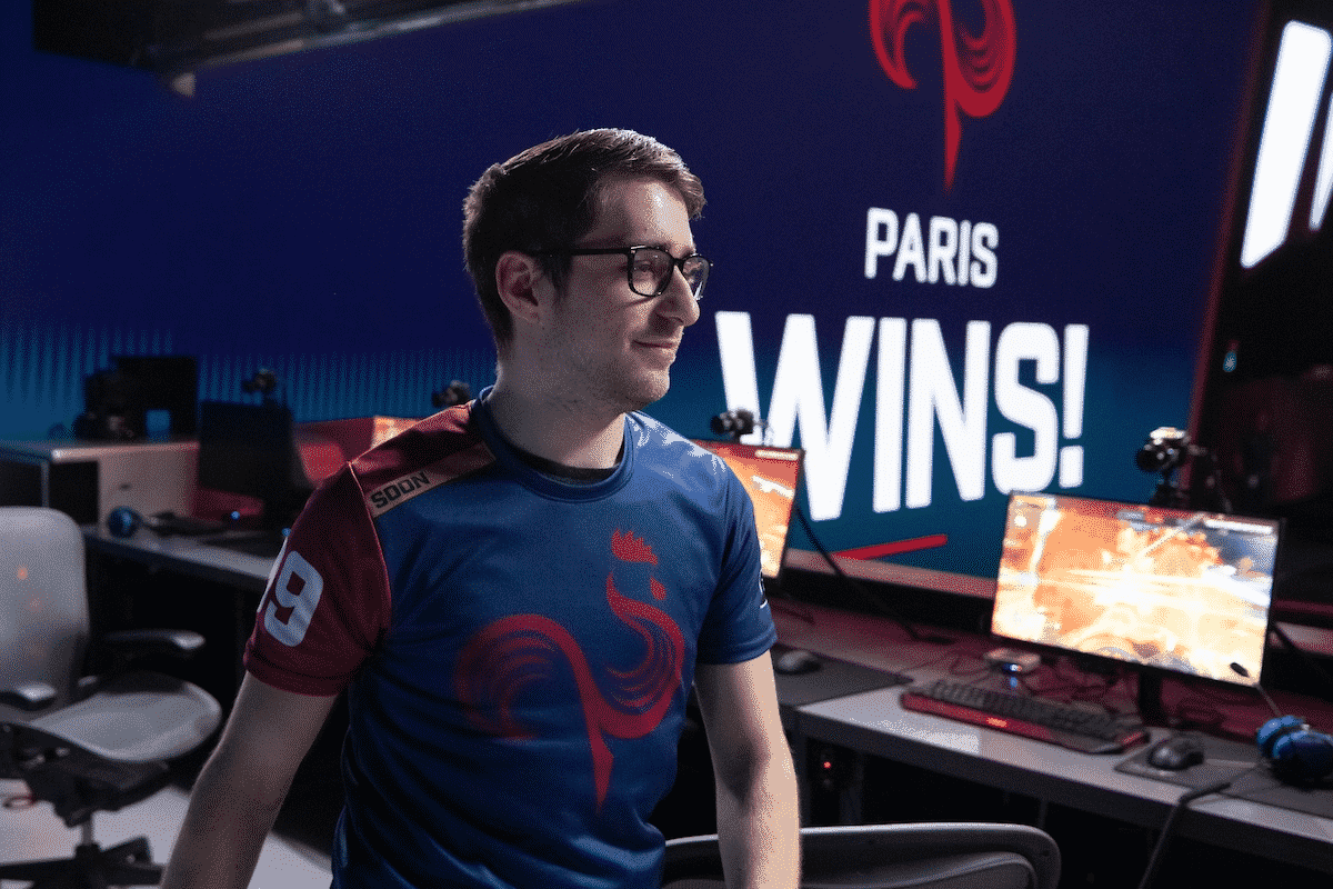 Paris Eternal Overwatch League player Terence "SoOn" Tarlier proudly walks on stage after a victory with a monitor in the background showing the Paris Eternal logo and the words "Paris Wins!"