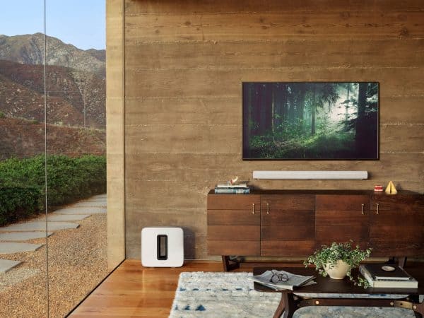 A living room setup is shown with a TV, coffee table and a Sonos Arc soundbar speaker