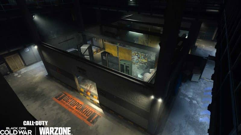 A picture of a militaristic compound with bright lights on the tops of ceilings and the word "Warzone" imposed on the bottom left for Call of Duty Black Ops Cold War