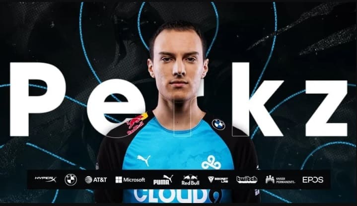 Pro LoL mid laner Luka "Perkz" Perković stands in a blue and black C9 jersey with his name and an outlined C9 logo behind him and a bunch of sponsorship brand logos in a row on the bottom