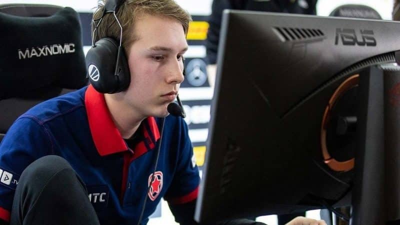 Pro Dota 2 player Danil "gpk" Skutin sits hunched over in front of a PC monitor on a stage before a professional match
