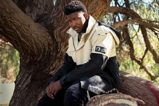 Dominique "King Vader" Barrett poses with a Team Liquid x Naruto Shippuden parka on on a tree