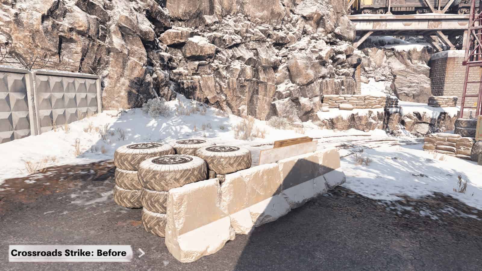 A screenshot from Call of Duty Black Ops Cold War map Crossroads pre-map changes. A cement roadblock with tires behind it is in the corner of the map with a larger wall and rock face behind them.