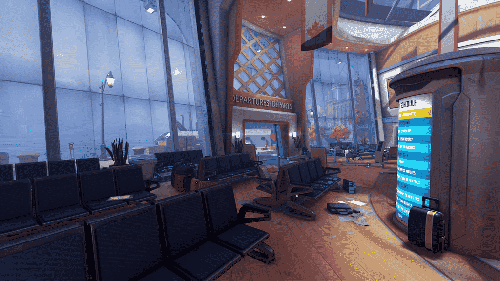 The inside of a station is shown from a screenshot of a new map in Overwatch. Empty chairs are lined up with a departure screen flashing in front and an open door leading outside with a Canadian flag above it.