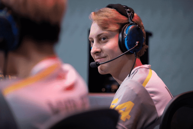 Pro Overwatch player Grant “Moth” Espe sits on the Overwatch League stage and smiles at a teammate to his left.