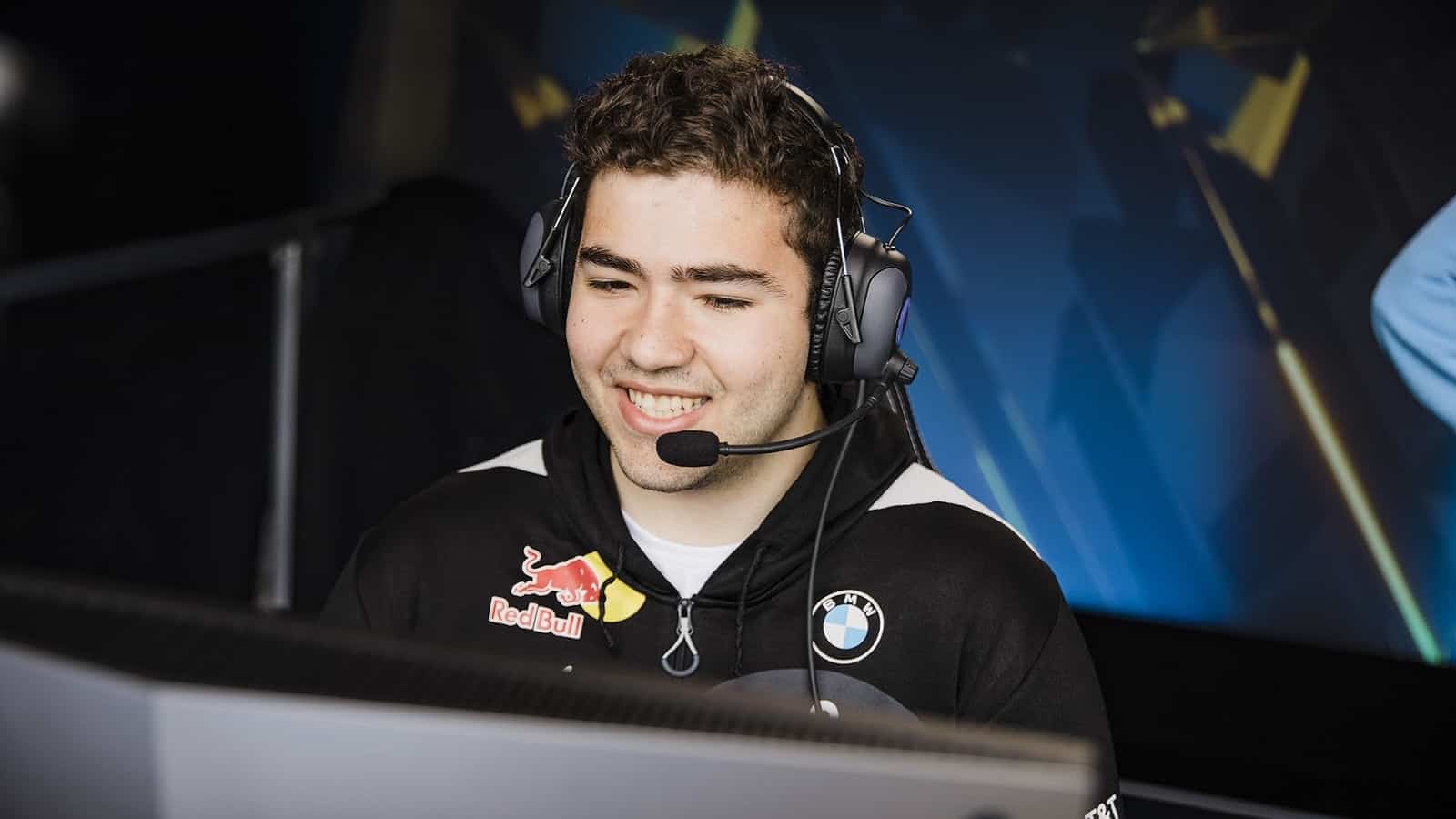 Pro LoL top laner for Cloud9 Ibrahim "Fudge" Allami smiles in front of a PC during an LCS stage.