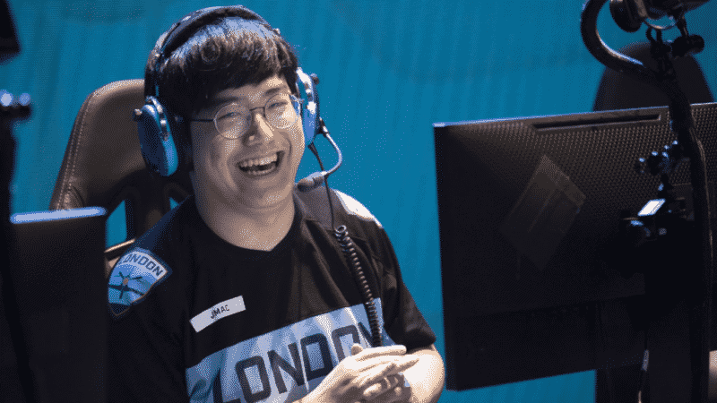 Former OWL player and current coach Dae-han "JMAC" Choi laughs on the OWL stage in front of a computer.