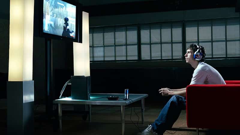 David "Walshy" Walsh sits and leans forward, playing Halo on a TV on the wall.