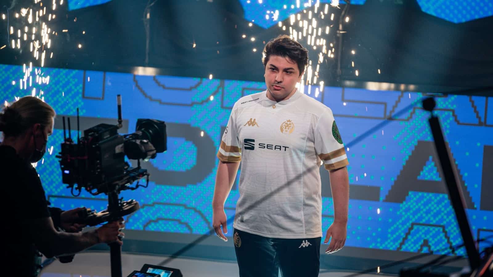 MAD Lions' İrfan “Armut” Berk stands confidently in front of a camera with spark flying behind him.