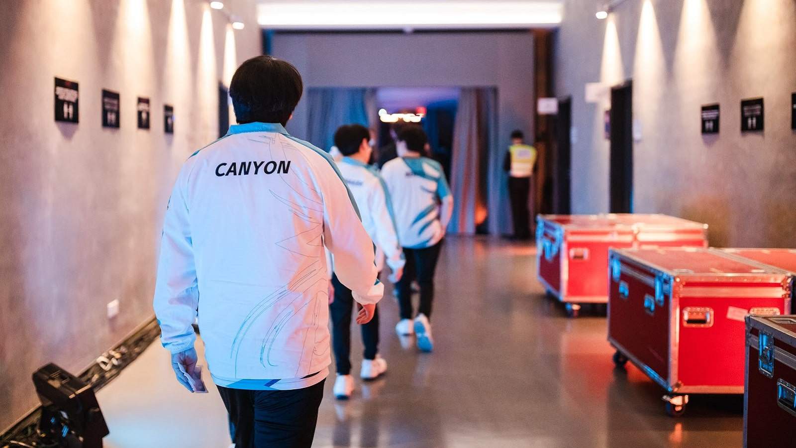 DAMWON KIA's jungler Kim "Canyon" Geon-bu walks with his back to the camera, following his teammates down a hallway.