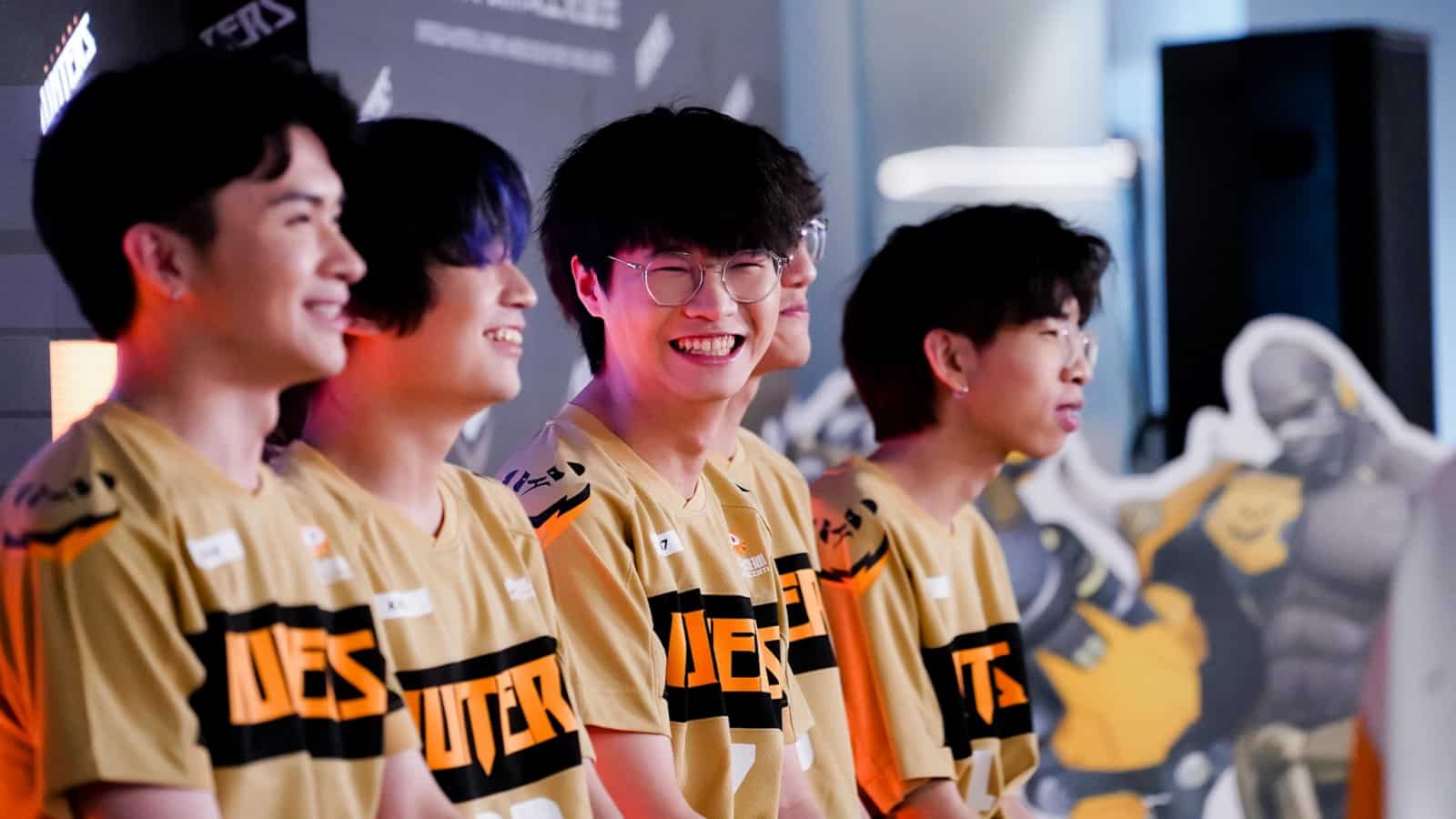 The Chengdu Hunters Overwatch League team sits together smiling, with one player beaming towards the camera.