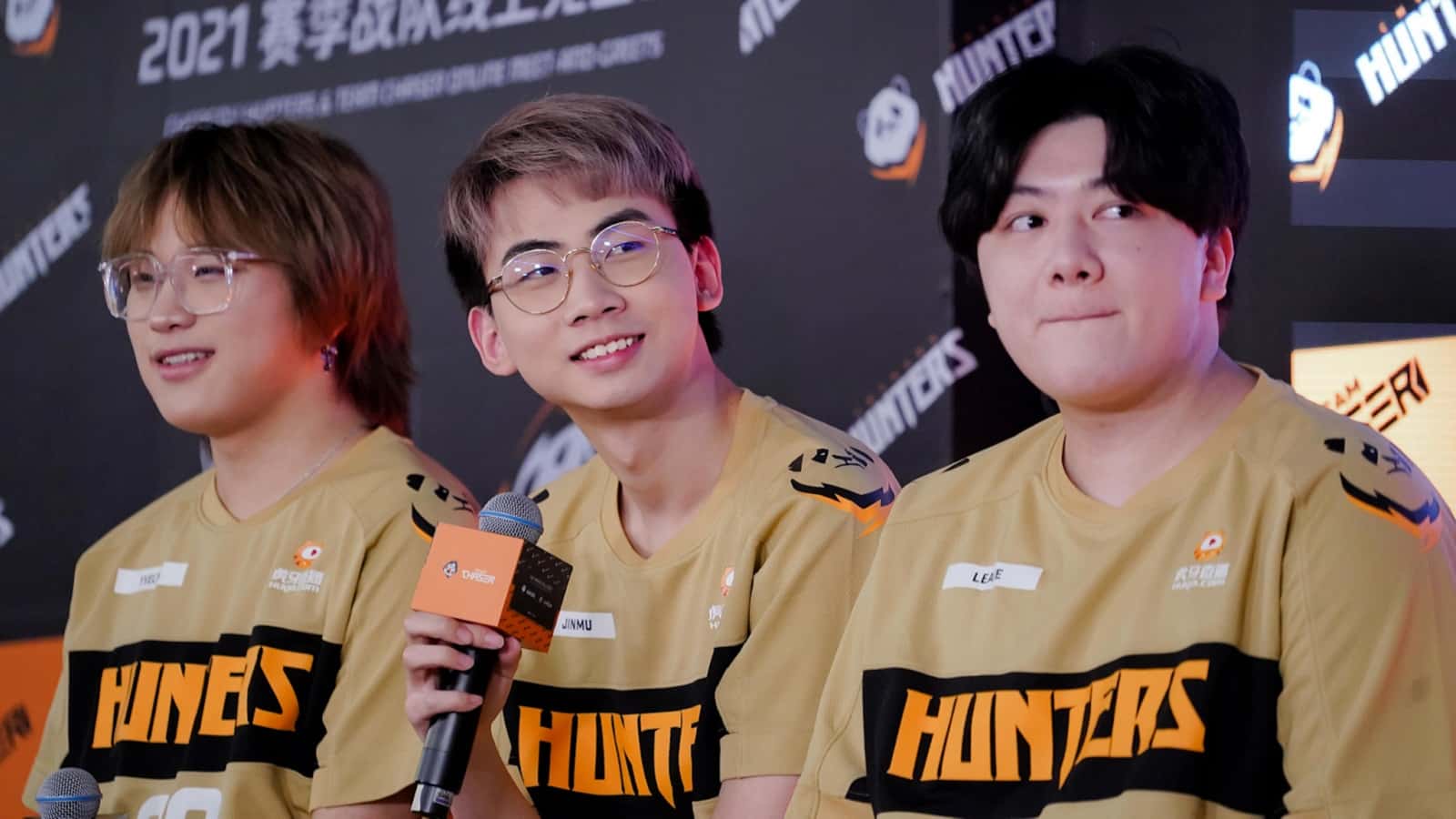 Three Chengdu Hunters Overwatch League players sit together for an interview, with one smiling and holding the microphone.