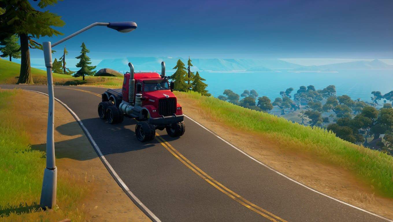 The Titano Mudflap vehicle, a red semi-truck, rolls down a hillside road in the chonkers off-road tires