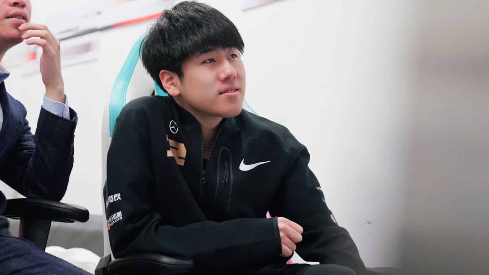 RNG Chen “Gala” Wei sits next to a coach and listens to someone else off-shot.