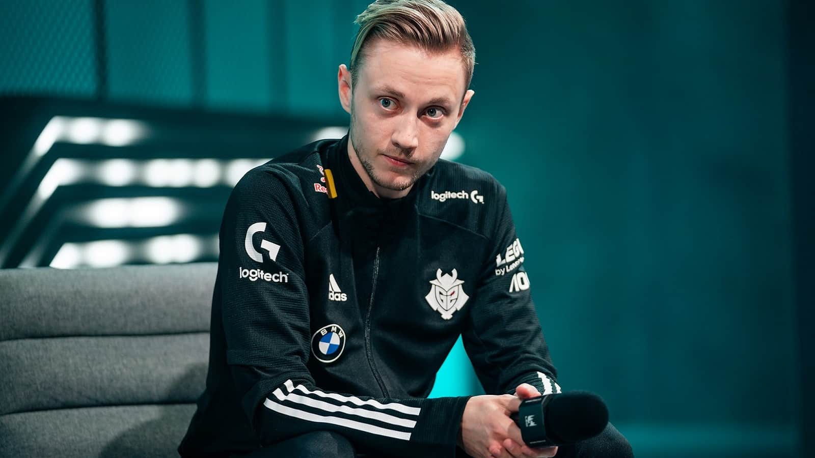 Martin "Rekkles" Larsson holds a microphone and sits on a couch during an LEC interview.