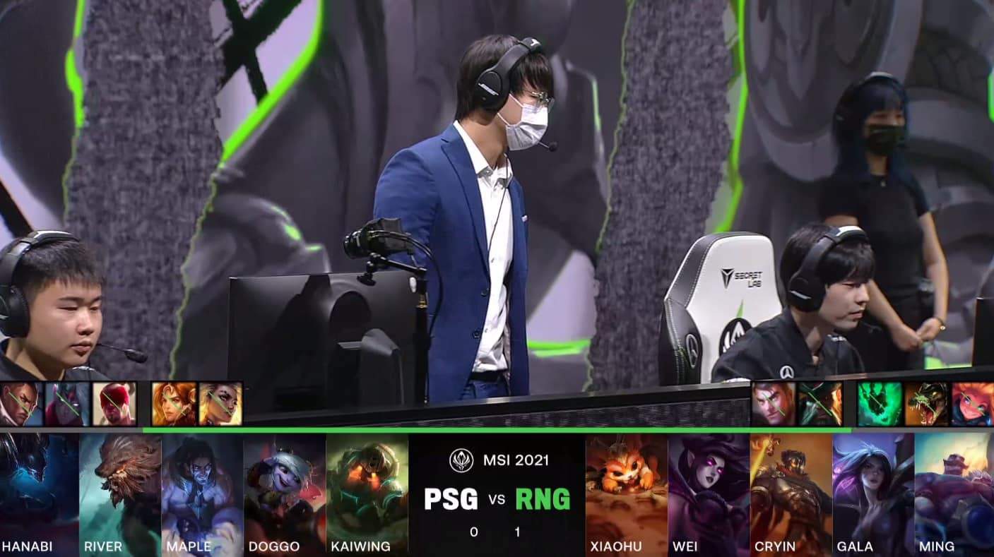 A screenshot from the LoL Esports broadcast for the Mid-Season Invitational (MSI) Semifinal match between Royal Never Give Up (RNG) and PSG.Talon. The picked and banned champion drafts appear at the bottom of the image with a shot of the RNG coach and two players on stage above.