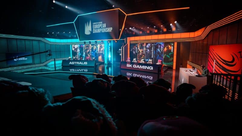 The LEC stage in Berlin is colored in orange and blue lights with the team names "Astralis" and "SK Gaming" on long monitors.