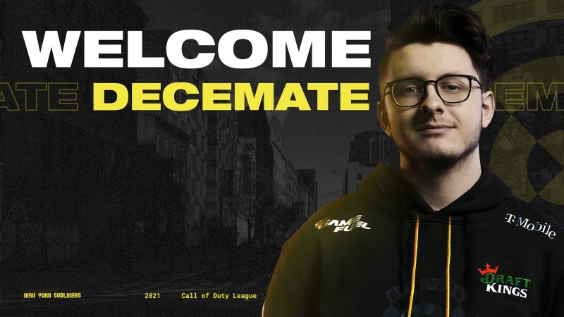 Jacob “Decemate'' Cato stands infront of an image of the NYC skyline in black and white. Next to him the words "Welcome Decemate" appear in bold white and yellow font