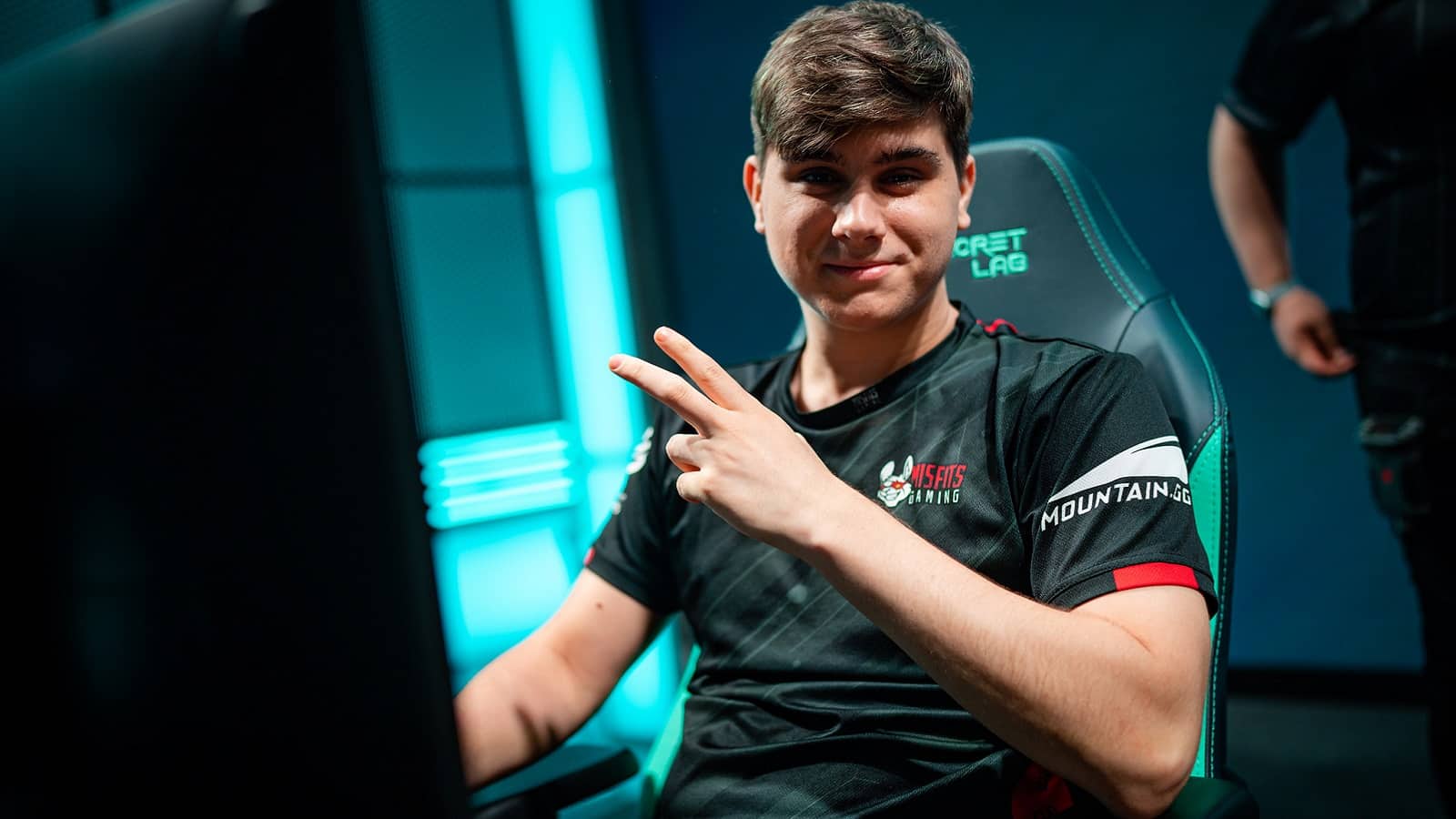 Pro LoL player Iván "Razork" Martín Díaz wears his Misfits Gaming jersey on the LEC stage and gives the camera a "V" sign with his hand.