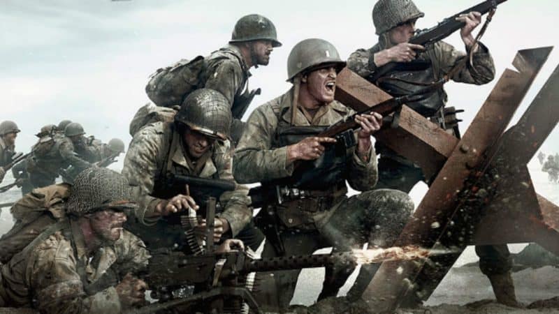 Men in WW II style military fatigues fire guns at enemies from behind anti tank obstacles