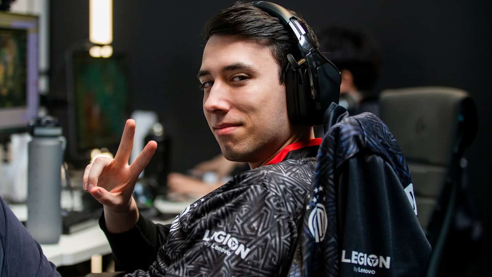Tristan "PowerOfEvil" Schrage makes a peace sign with his hand with a smirk on his face in TSM attire.