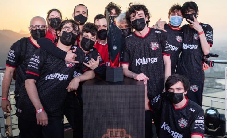 The RED Canids LoL players and staff pose together around the CBLOL trophy after winning the championship.
