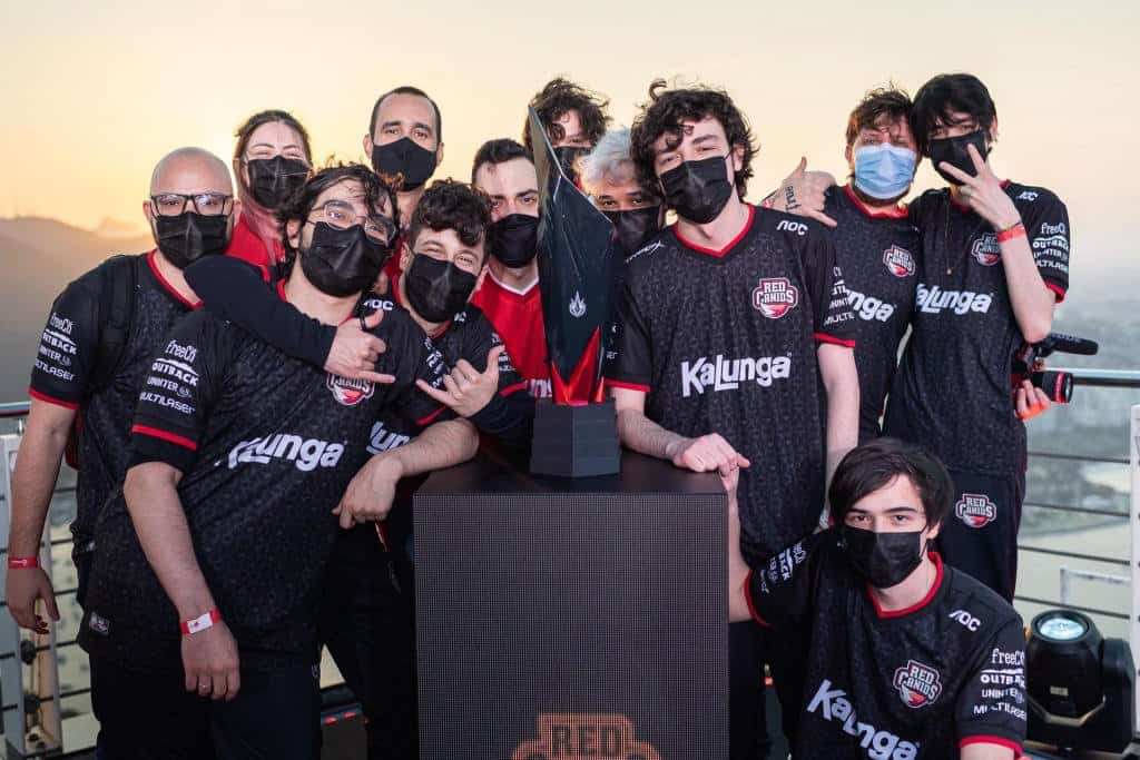 The RED Canids LoL players and staff pose together around the CBLOL trophy after winning the championship.