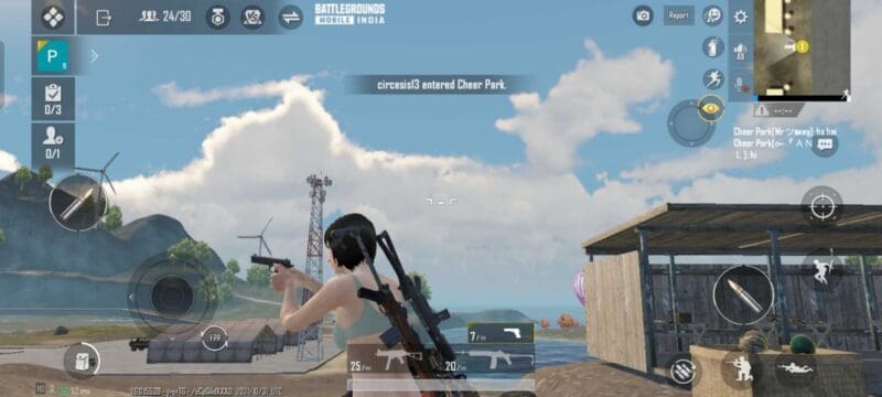 A female character from Battlegrounds Mobile India walks near a shed under a blue sky holding a pistol.
