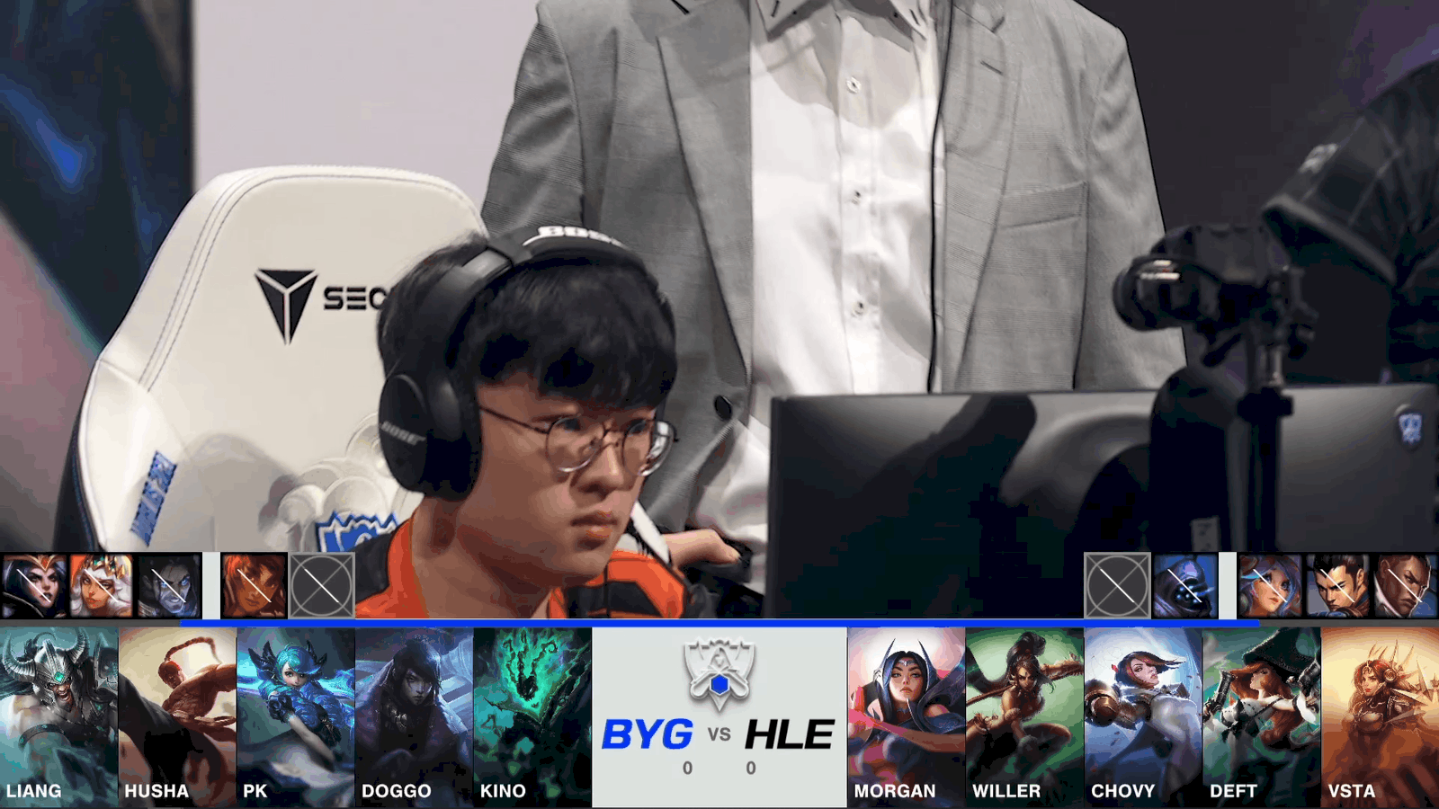 A screenshot from the 2021 World Championship Play-in Knockouts broadcast, showing the Game One drafts between Beyond Gaming and Hanwha Life Esports with a shot of a BYG player and coach on the Worlds 2021 stage above.