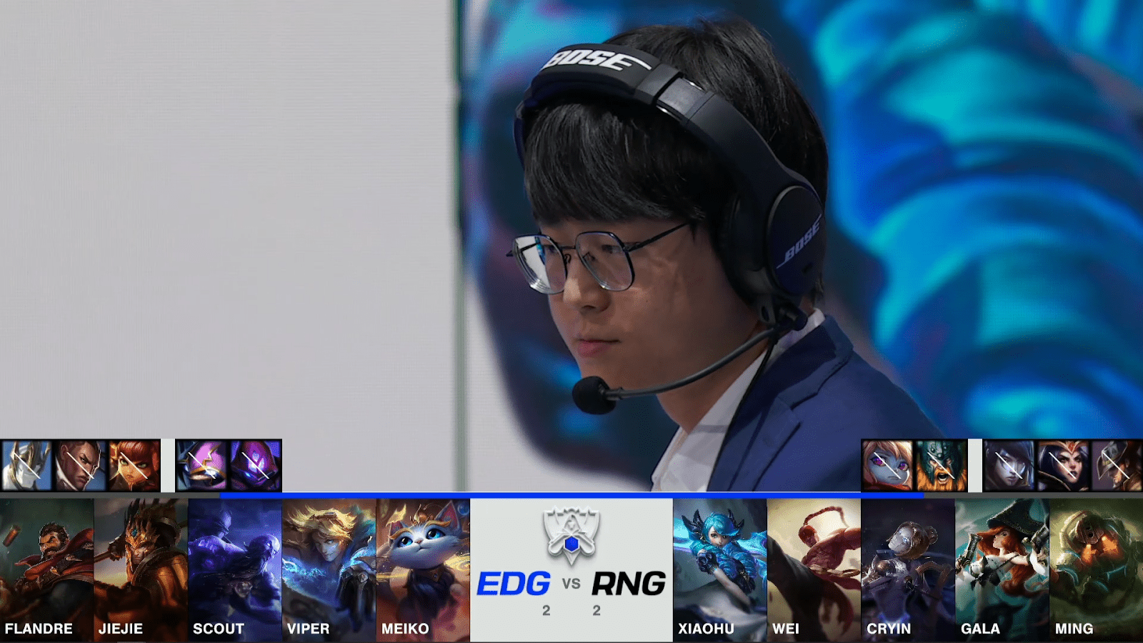 A screenshot from the 2021 World Championship Main Event Quarterfinals broadcast, showing the Game Five champion drafts between Royal Never Give Up and Edward Gaming with a shot of RNG coach Wong "Tabe" Pak Kan above.