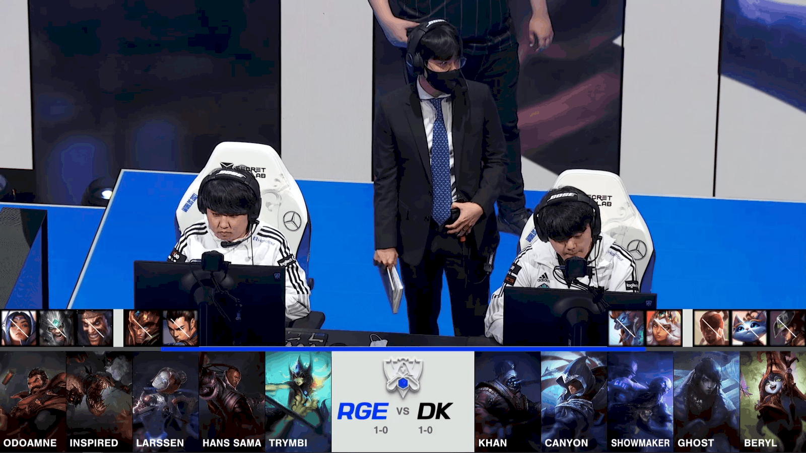 A screenshot from the 2021 World Championship Main Event Group Stage broadcast, showing the champion drafts between Rogue and DAMWON KIA with a shot of two DAMWON players and their coach on stage above.