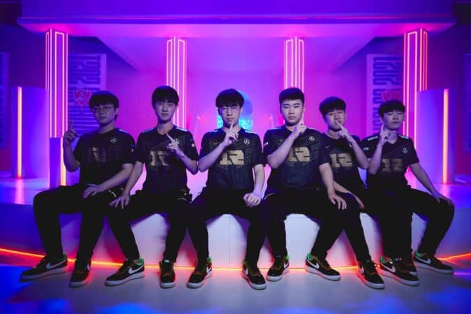 The roster for RNG pose for the camera against a background of neon lights at Worlds 2021