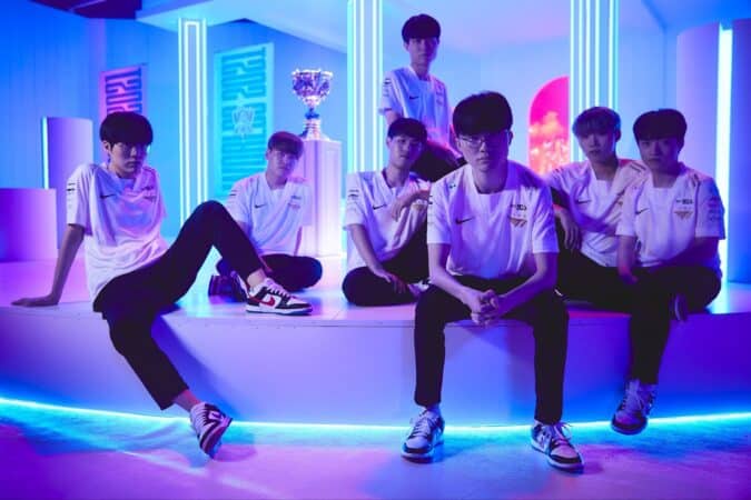 The roster for T1 lounge around a white set with blue lighting behind them