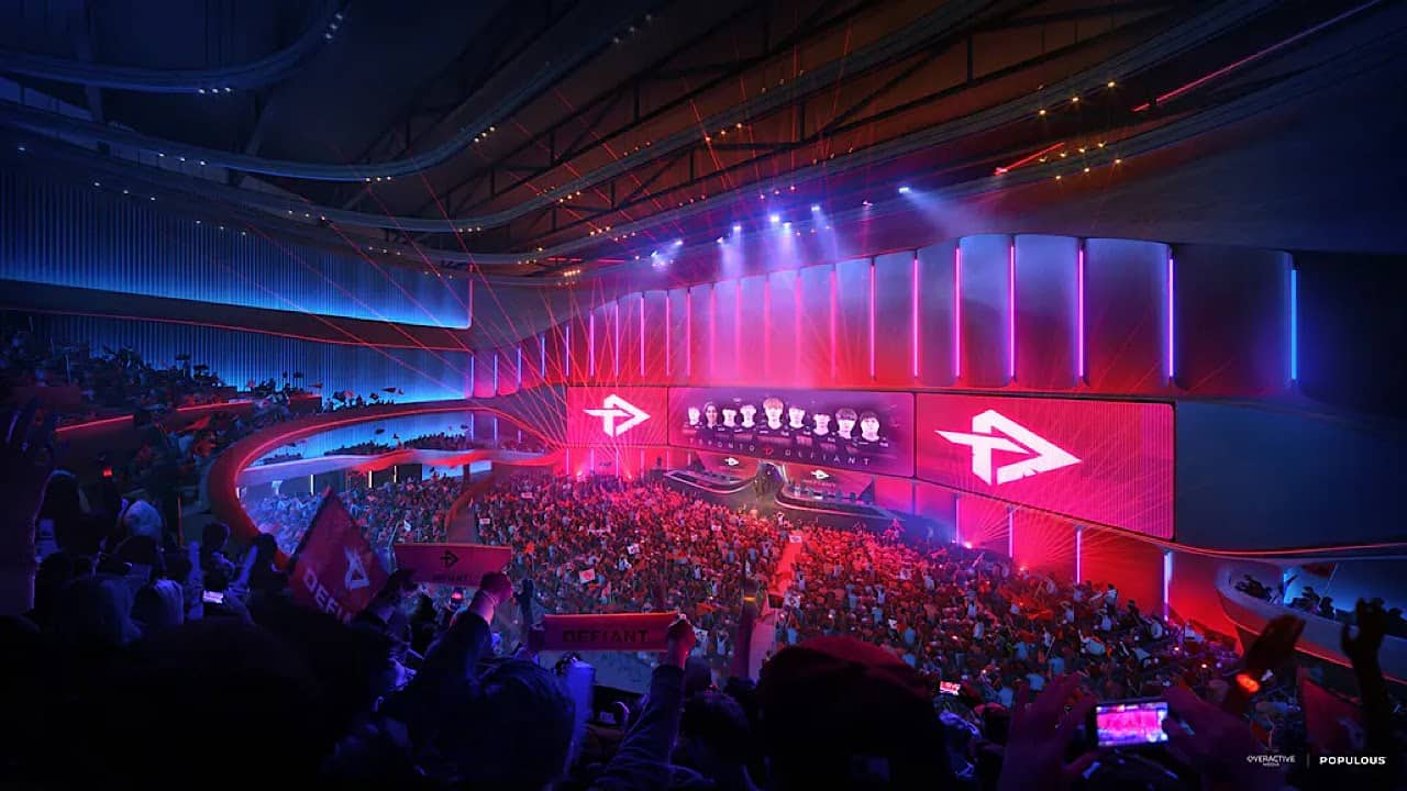 Populous’ render of the Overactive Media Performance Venue interior, showing a packed crowd waiting for an esports game to start with dim lighting except on stage.